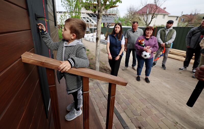 Pashka Pavliuk uses the key to unlock the door of his family’s new home as representatives from To Ukraine with Love and the Stirling Foundation present the new modular home to the family near Kyiv, Ukraine, on Thursday, May 4, 2023.