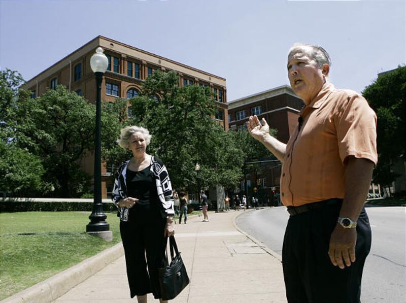 Bill and Galyle Newman talk about President John F. Kennedy as they stand in front of the Texas School Book Depository in Dallas.