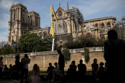 Workers, top, fix a net to cover one of the iconic stained glass windows of the Notre Dame Cathedral in Paris, Sunday, April 21, 2019. The fire that engulfed Notre Dame during Holy Week forced worshippers to find other places to attend Easter services, an