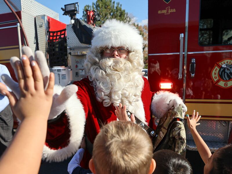 Santa high-fives students before he and Salt Lake City Firefighters Union Local 81 members delivered coats on Nov. 15, 2022.