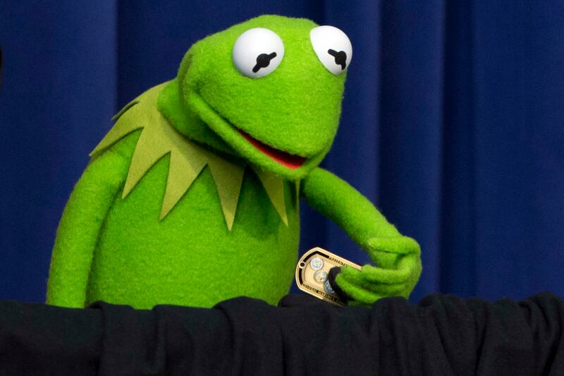Kermit the Frog holds Chairman of the Joint Chiefs of Staff Gen, Martin Dempsey's challenge coin after the General gave the muppet the coin at an event for children of military families in the South Court Auditorium of the Eisenhower Executive Office Buil