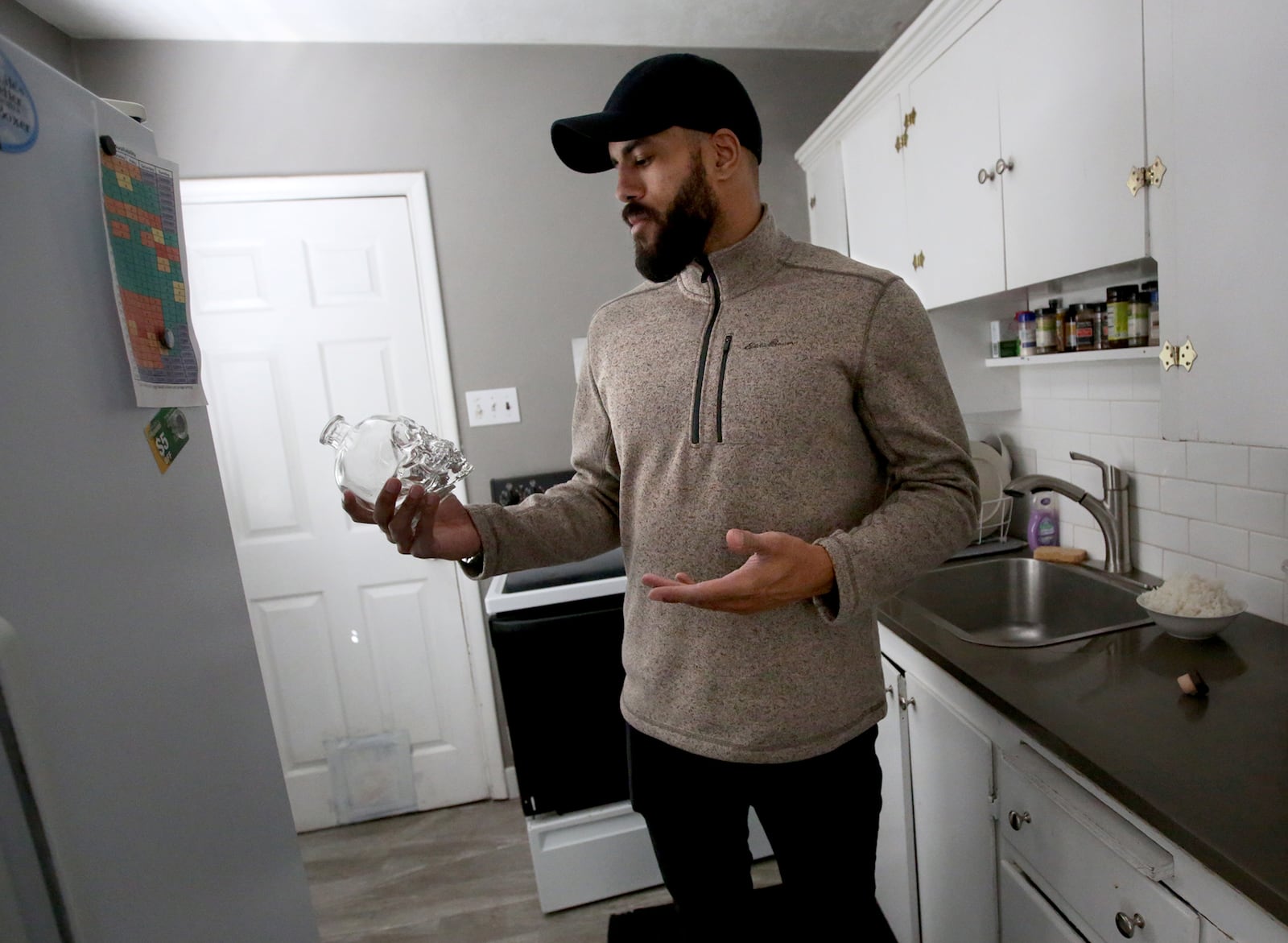 Christian Tyler holds a bottle that belonged to his best friend and cousin, who was shot to death, at his home in Salt Lake City on Monday, March 26, 2018.
