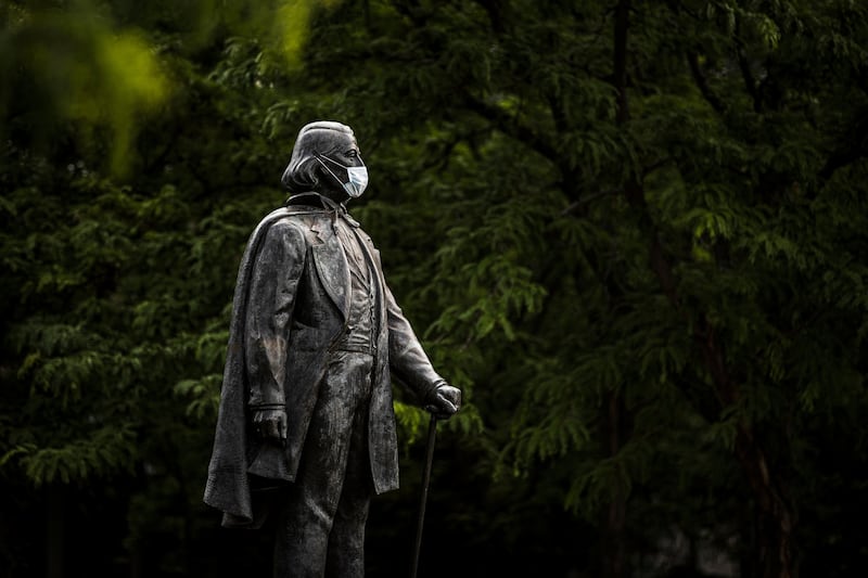 A statue of Brigham Young on the BYU campus in Provo wears a blue disposable mask.