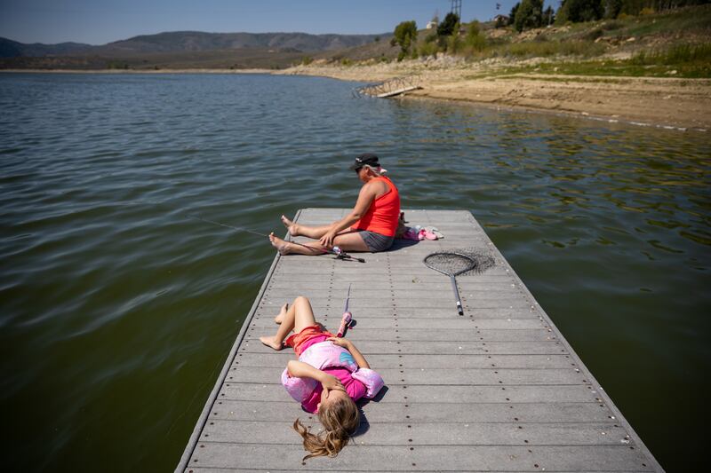 Presley Morse, 6, lies on a dock while fishing with her mother, Jill Gilson, while they camp at Scofield State Park.