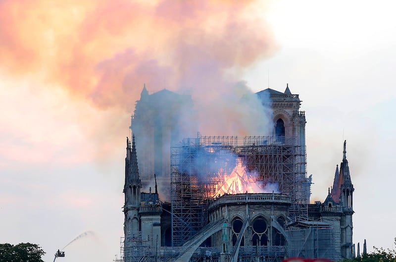 A firefighter tackles the blaze as flames and smoke rise from Notre Dame cathedral as it burns in Paris, Monday, April 15, 2019. Massive plumes of yellow brown smoke is filling the air above Notre Dame Cathedral and ash is falling on tourists and others a