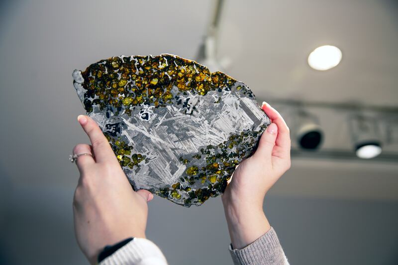 Christie’s auction house sale coordinator Gillian Hawley holds a rock and metal meteorite that was once part of an asteroid in New York on Feb. 8, 2021. The Maine Mineral & Gem Museum is offering a $25K price to whoever finds a piece of meteorite that landed in Maine.