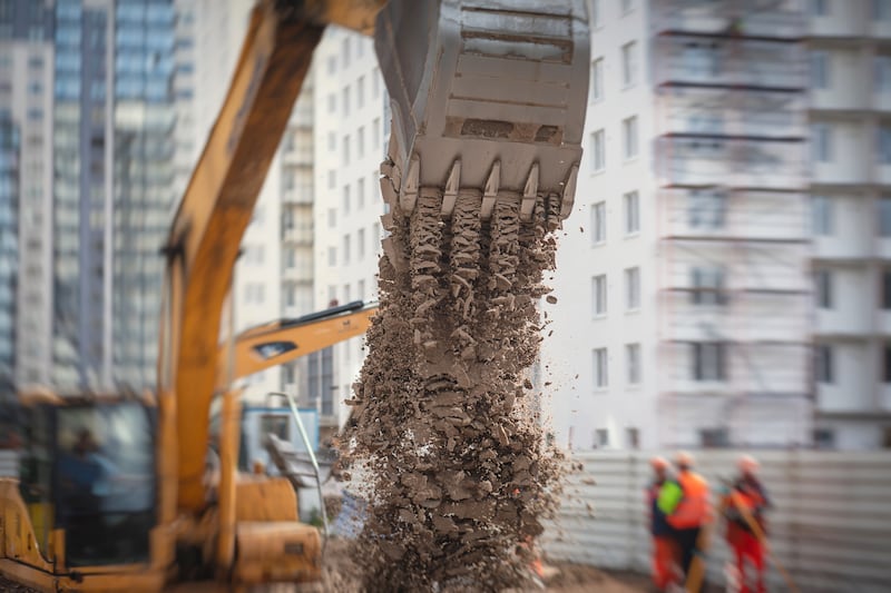 A bulldozer drops a pile of dirt while digging the foundation for a new building.