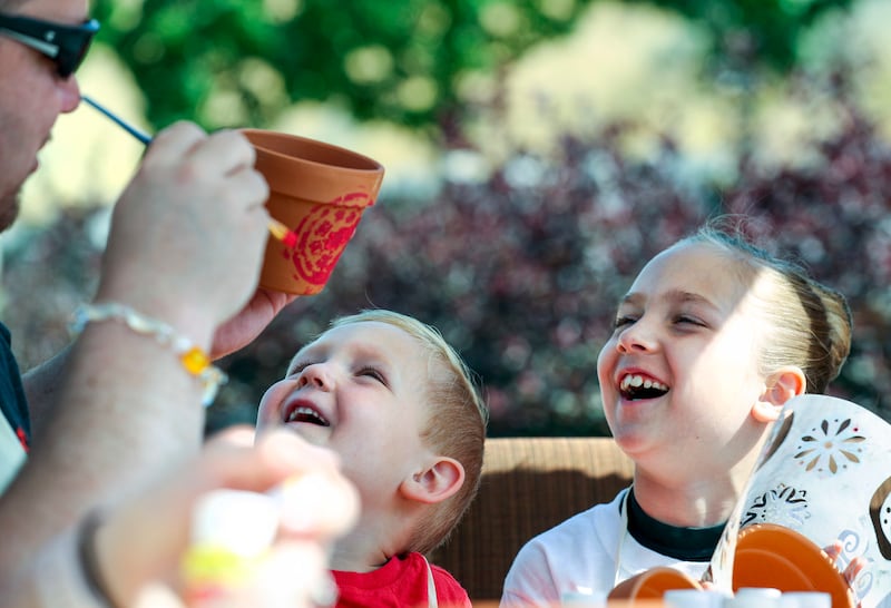 Chad Jaggi shows his children, Braden and Bella, his painting on a flower pot during a sunflower planting party in honor of Sarcoma Awareness Month at the Huntsman Cancer Institute in Salt Lake City on Monday, July 30, 2018. Jaggi has angiosarcoma, a rare
