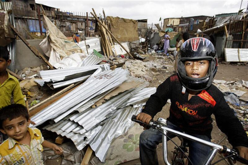 "Slumdog" star Azharuddin Mohammed Ismail rides a bicycle, a gift from a fan, past torn-down shanties.