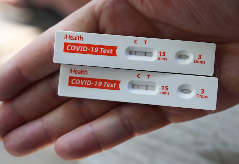 COVID-19 antigen rapid tests held in a hand indicate positive results.