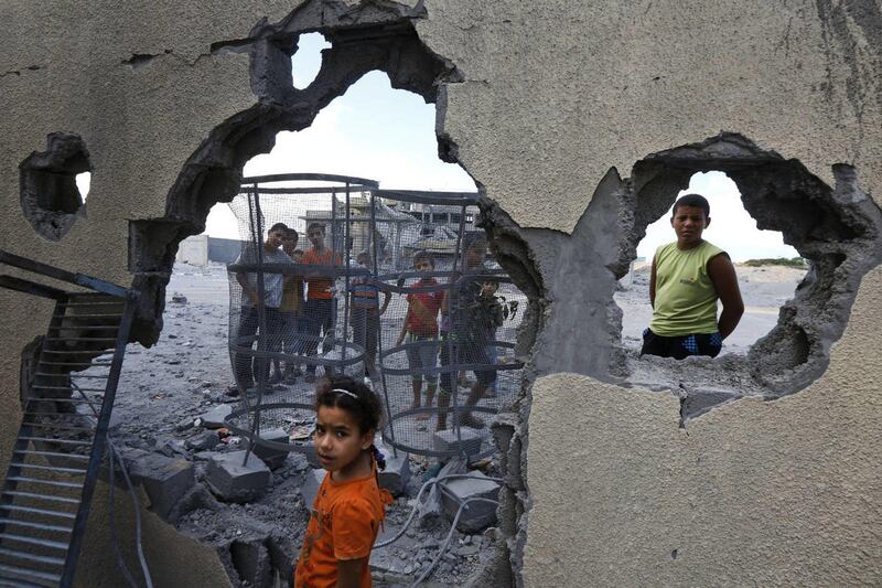 Palestinian Suma Abu Mahsen, 7, stands by a damaged wall of a house following an overnight Israeli missile strike to a nearby transition center for newly released convicts, that was not yet operational, in Rafah, southern Gaza Strip, Tuesday, July 15, 201