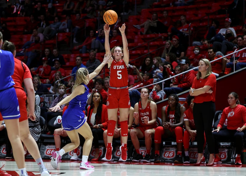 Utah Utes guard Gianna Kneepkens, wearing red, puts up a 3-point shot over BYU Cougars guard Paisley Harding