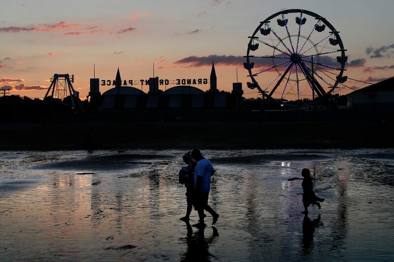 Visitors walk near the Palace Playland amusement park Wednesday, Aug. 5, 2020, at Old Orchard Beach, Maine. Tourists have returned to the popular seaside town in a state that ranks one of the lowest in the nation in positive cases of coronavirus.