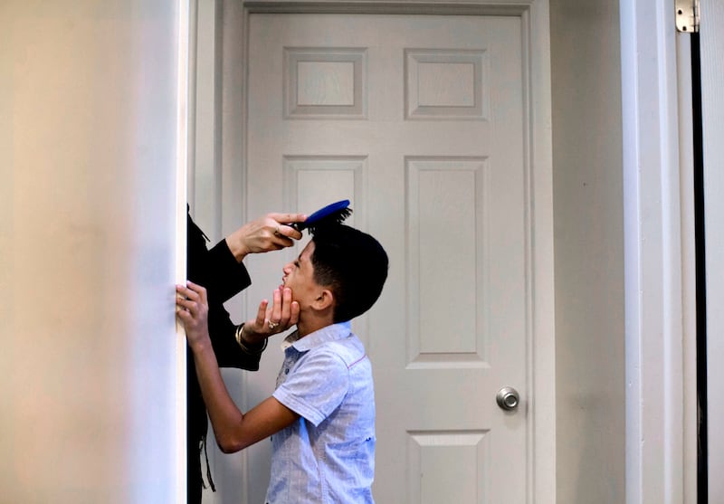 Baraa Huraideen brushes Abdullah Hamad's hair on Wednesday, Aug. 23, 2017, the morning of his first day of school at the Tumaini Welcome & Transition Center on Aug. 23. Abdullah and his brothers will spend two weeks at the center before heading to their n