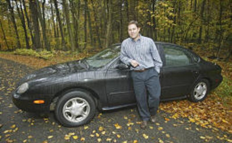 Frank Ribezzo, an attorney, poses with his 1997 Ford Taurus GL, his third Taurus. Next week, Ford says it will stop production of the popular family sedan.