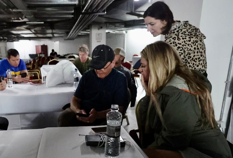 Utah Senate President Stuart Adams, R-Layton, To Ukraine With Love founder Svitlana Miller, center, and Wander COO Tiffany Vail consult the Signal and Air Alert! apps for updates on air strikes near the Kyiv Oblast (region).