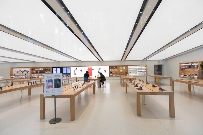 Two Apple employees work inside the closed store, Monday, March 16, 2020 in New York. Apple is closing its stores until March 27. (AP Photo/Mark Lennihan)