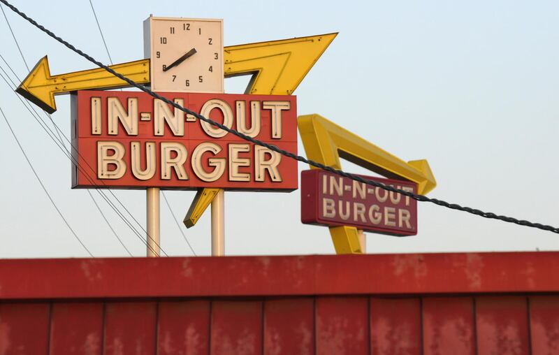 In-N-Out Burger signs, one the foreground from the fast food chain's original location, and one in the background at its new location across the Interestate 10 freeway, are seen on Tuesday, June 8, 2010, in Baldwin Park, Calif. (AP Photo/Adam Lau)