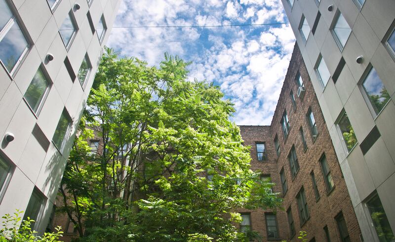 A patio garden view shows a seven-story modern modular apartment building called the Stack, on either side of a decades-old residence, Wednesday, July 9, 2014, in the Innwood neighborhood of New York. The Stack’s 28 apartments were formed from 59 modules of rectangular components all 12.5 feet wide and 50 to 60 feet long. It�s billed as the first multistory, modular-built apartment building to open in the city. (AP Photo/Bebeto Matthews)