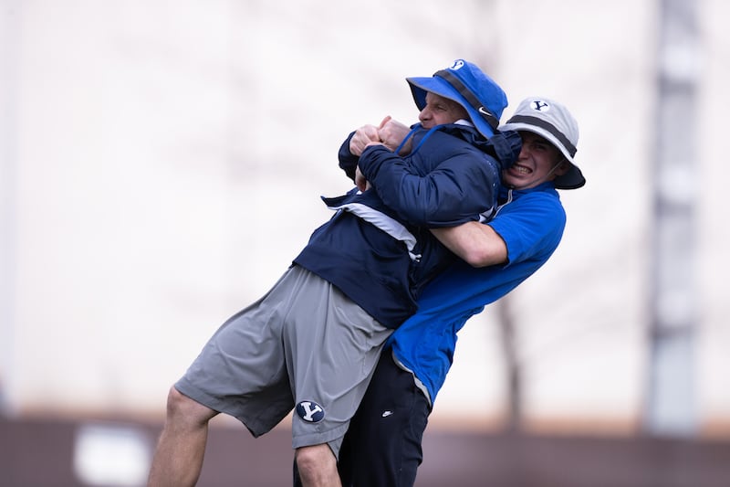 BYU tight ends coach Steve Clark, left, gets hugged by his son Jamison, now an assistant coach on the Utah Tech staff.