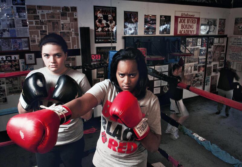 In this photo taken Feb. 29, 2012, Grand Blanc High School seniors Tanjae Chairse, 18, right, and Caitlin Williams, 17, pose for photos at Joe Byrd Boxing Academy in Mt. Morris Township, Mich. Charise and Williams, who have never boxed but say the sport i