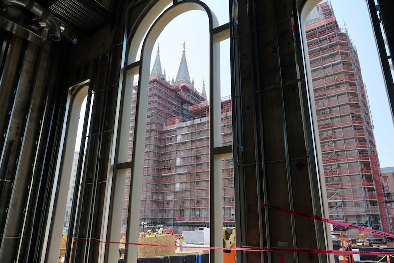View of the Salt Lake Temple, surrounded in scaffolding, through an arched opening.
