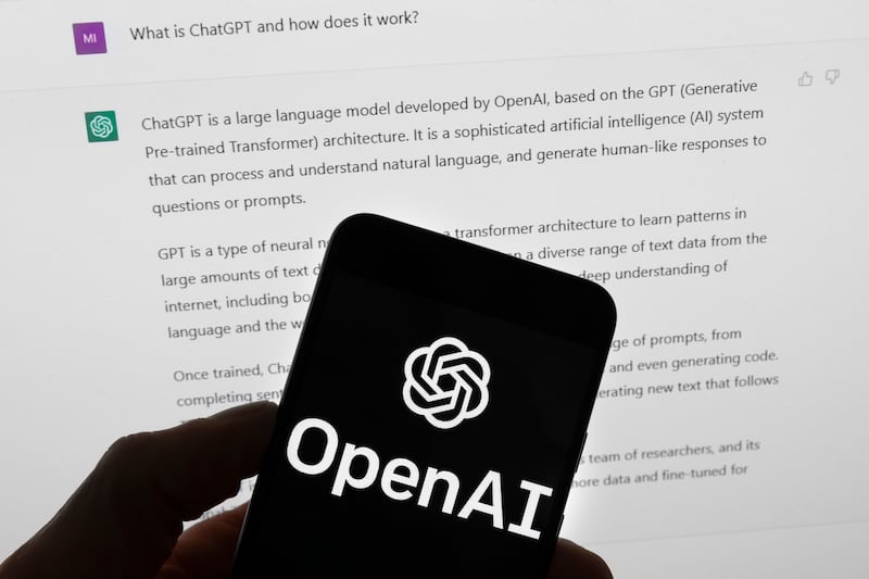 The OpenAI logo is seen on a mobile phone in front of a computer screen on Tuesday, March 21, 2023, in Boston.