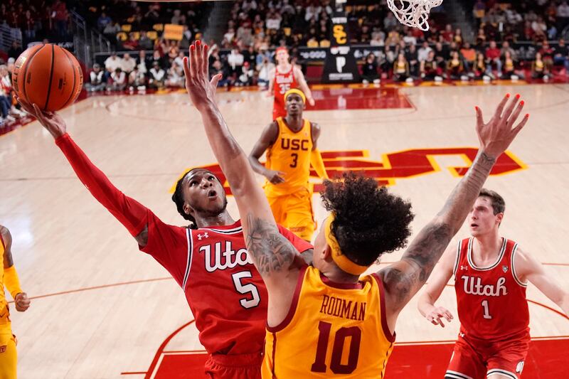 Utah guard Deivon Smith, left, shoots as Southern California forward DJ Rodman defends during the first half of an NCAA college basketball game Thursday, Feb. 15, 2024, in Los Angeles.