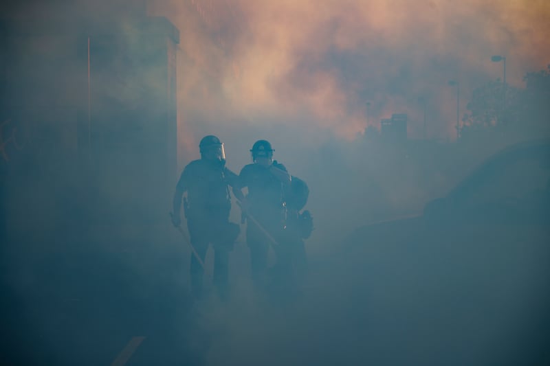 Police officers walk through a cloud of tear gas, Thursday, May 28, 2020, in St. Paul, Minn. Protests over the death of George Floyd, a black man who died in police custody Monday, broke out in Minneapolis for a third straight night.