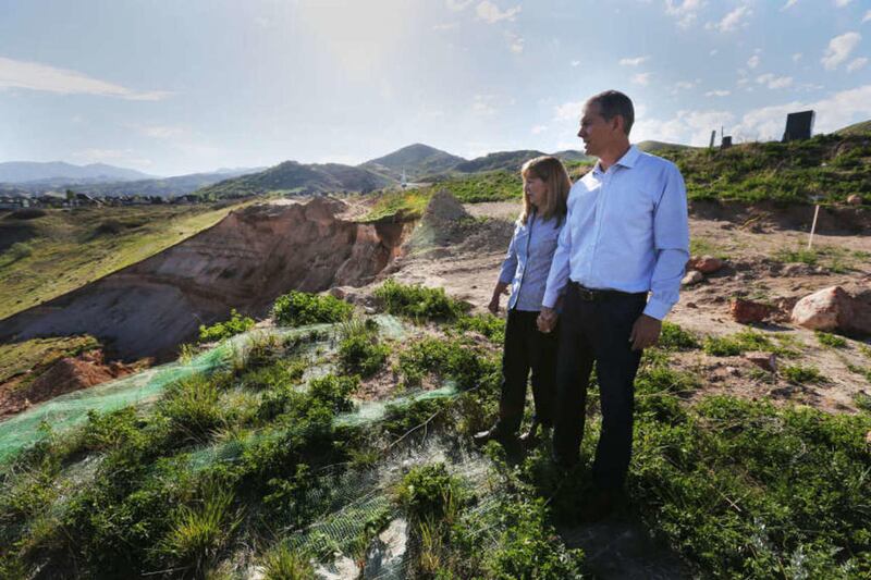 Jeanette and Paul Evans stand near their home with a landslide at left in North Salt Lake Thursday, April 30, 2015.
