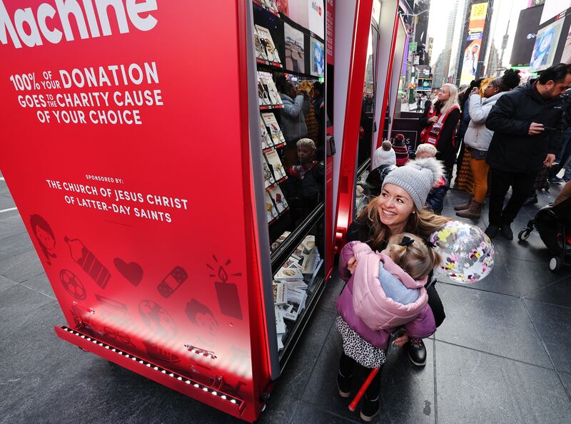Estee Carter holds her daughter Darbi after donating with Light The World Giving Machines in Times Square.
