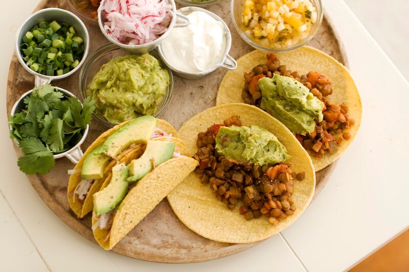 Pulled pork tacos and lentil tacos are served on a plate.