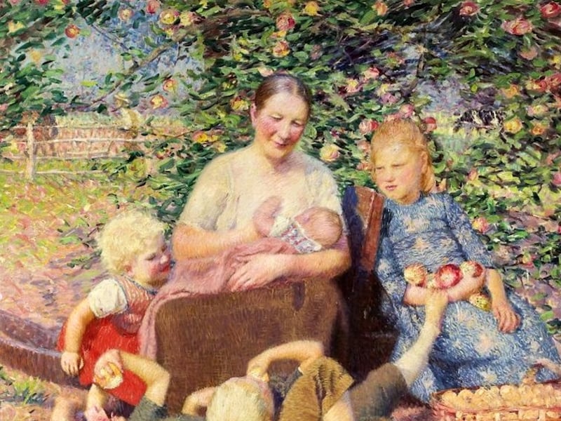 A woman sits underneath an apple tree while children around her. She holds a baby to her chest and has a basket in front of her.