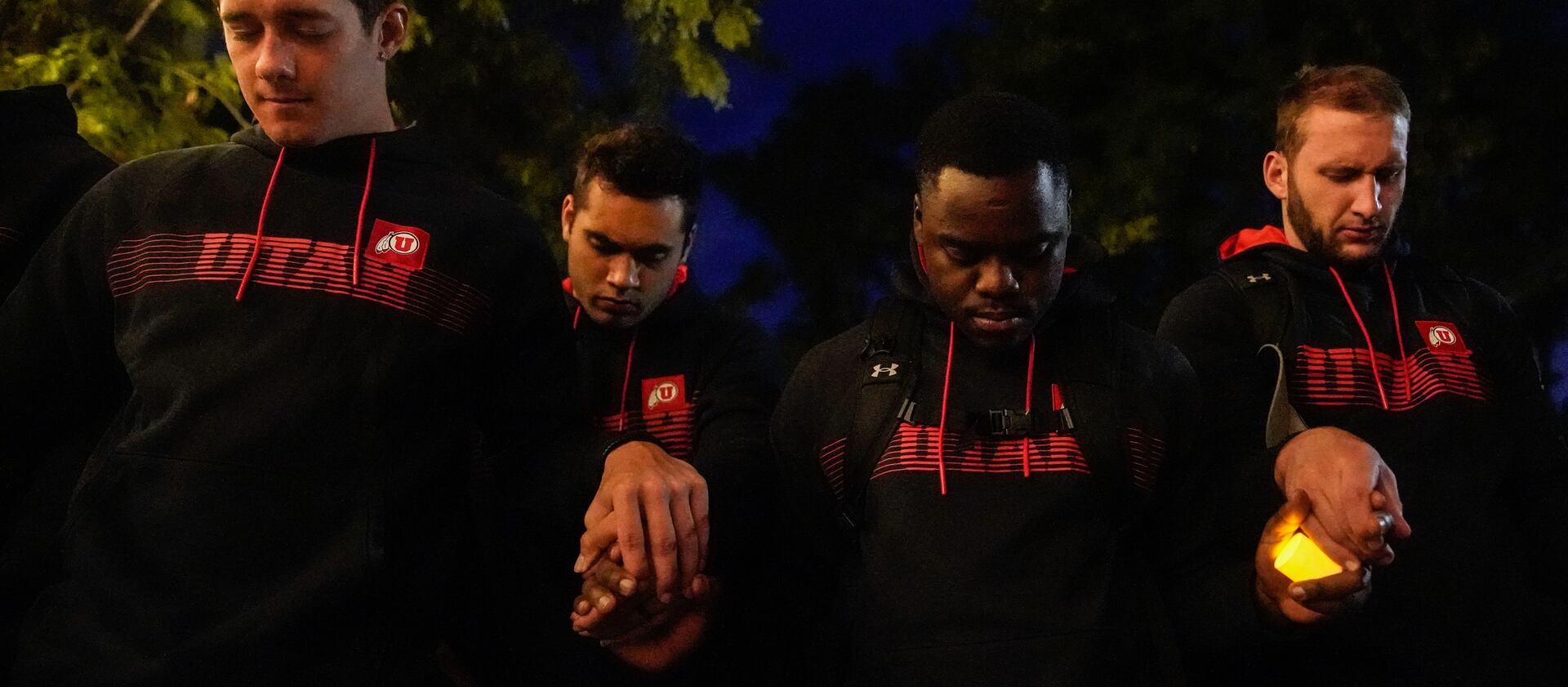 University of Utah football players hold hands as they pray during a vigil for slain football defensive back Aaron Lowe.