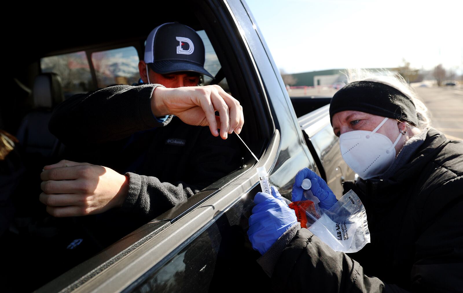 Registered nurse Paula Moffitt collects a COVID-19 nasal swab from Nathan Graham at the University of Utah in Salt Lake City on Monday, Jan. 31, 2022.