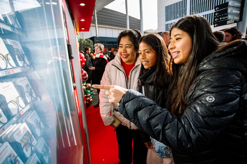 A mother with her two daughters select an item to donate using one of the new Giving Machines located in Barcelona, Spain, on Nov. 28, 2025.