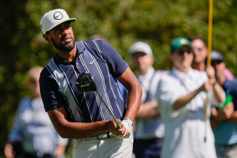 Tony Finau, wearing blue, watches his tee shot on the 15th hole at the Masters.