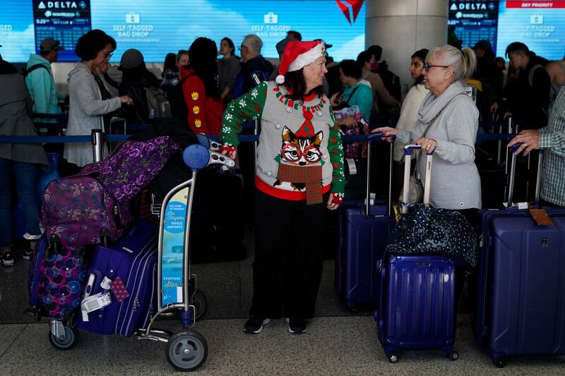 Bonnie Welsh, 62, in a Santa hat, chats with a fellow traveler while waiting in line to check in at Los Angeles International Airport on Dec. 19, 2022.