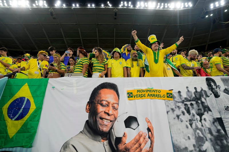 Brazil supporters cheer above a banner with pictures of soccer legend Pele, while waiting for the World Cup match between Brazil and South Korea.
