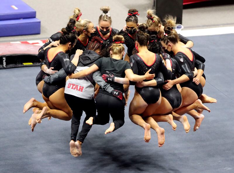 The University of Utah’s Red Rocks gymnastics team huddles in a circle and jumps up in the air in a cheer as at the Huntsman Center in Salt Lake City on Friday, Feb. 26, 2021.