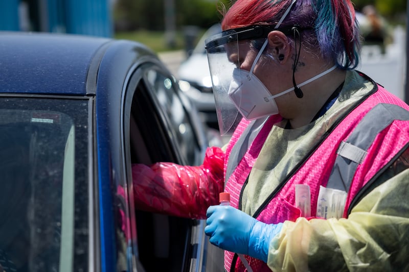 Megan Clay administers a COVID-19 test at a NOMI Health drive-thru test site in West Valley City.