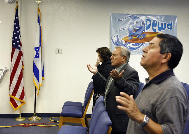 Parishioners pray by U.S. and an Israeli flags while Pastor Richard Escobedo, not shown, leads the Centro Palabra de Fe Church's congregation during it's Sunday morning service in Compton, Calif., July 27.