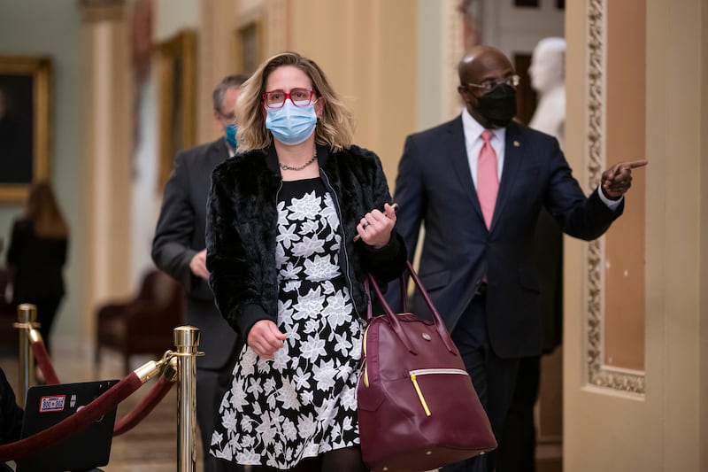 Arizona Sen. Kyrsten Sinema and Georgia Sen. Raphael Warnock walk in the U.S. Capitol in February 2021.