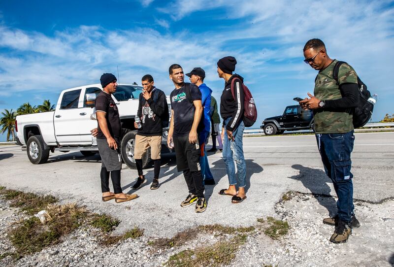 A group of Cuban migrants stand in the sun on the side of U.S. 1 in the Middle Keys island of Duck Key, Fla.