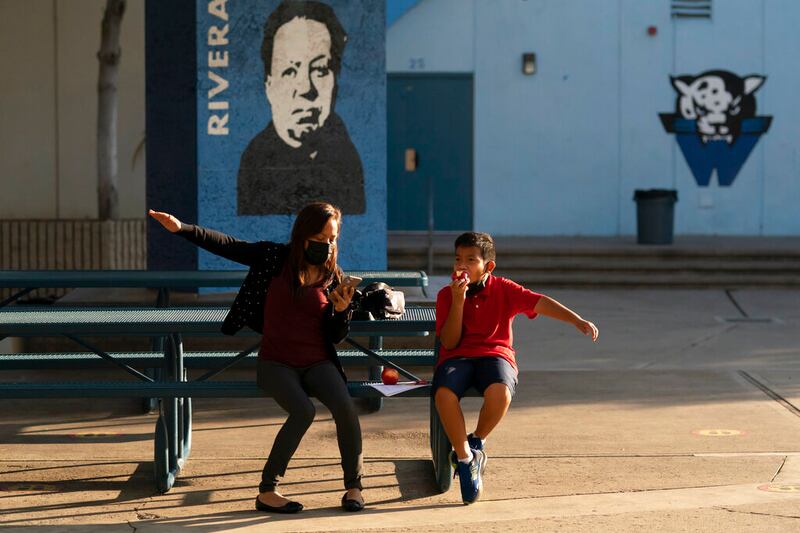 Alex Esperides and his mother, Josefina Jimenez, move their arms in the holding area after they received the Pfizer COVID-19 vaccine.