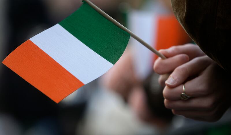 Hands hold an Irish flag.