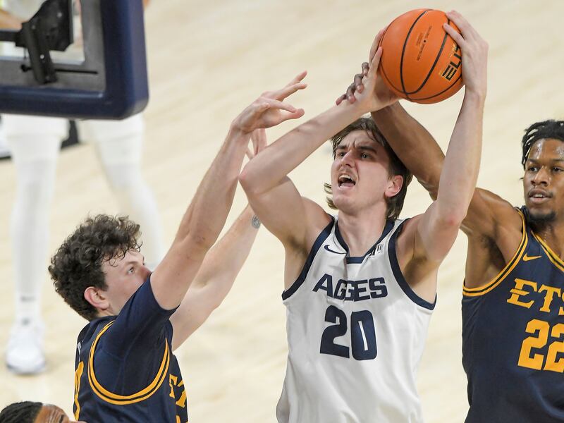 Utah State’sIsaac Johnson (20) shoots as East Tennessee State’s Braden Ilic, left, and forward Jaden Seymour (22) defend.