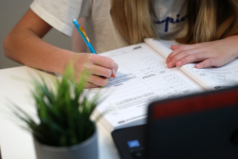 Charlotte Perry writes in a workbook as she participates in school via their computers at home in Salt Lake City.