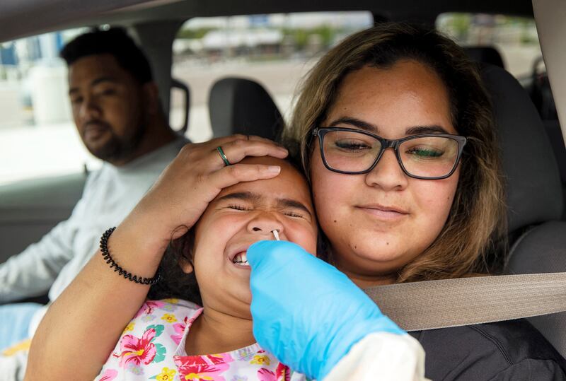Justina Alatini holds her daughter, Tialani Alatini, as she reacts to a COVID-19 test.