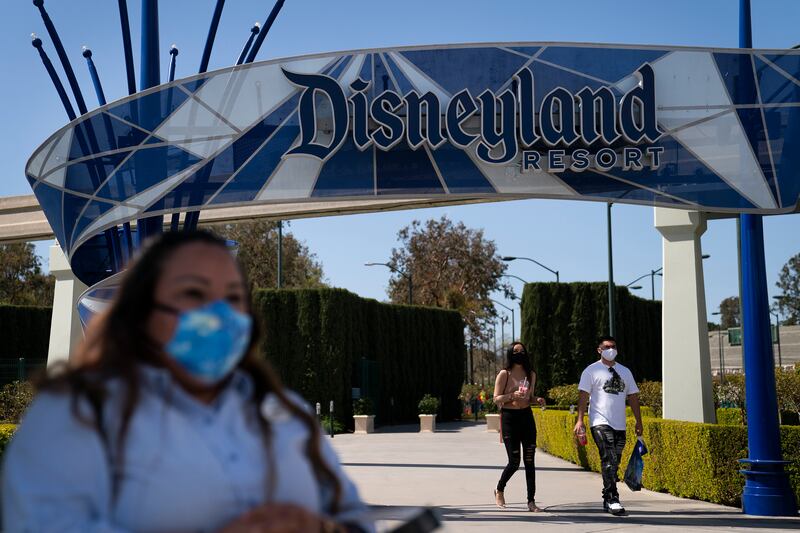 A woman with a face mask waits to cross the street outside Disneyland Resort in Anaheim, California.